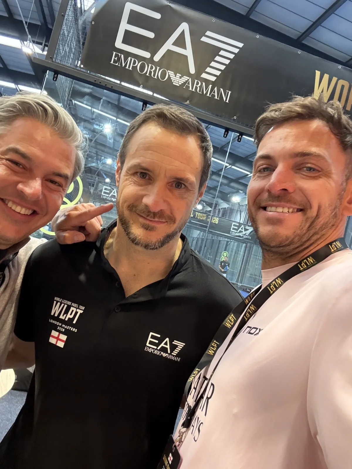 Carlo Cudicini in his black WLPT London Masters polo with two of the PadX and Genius Digital Labs team, beneath the EA7 Emporio Armani banner over the courts.